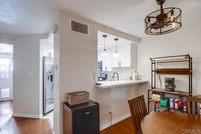 kitchen featuring fridge, white cabinetry, hanging light fixtures, dark wood-type flooring, and stainless steel fridge with ice dispenser