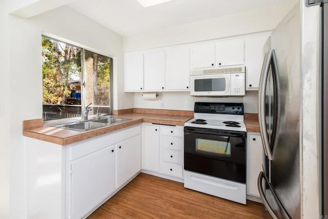 kitchen featuring sink, white cabinetry, electric range oven, and stainless steel refrigerator