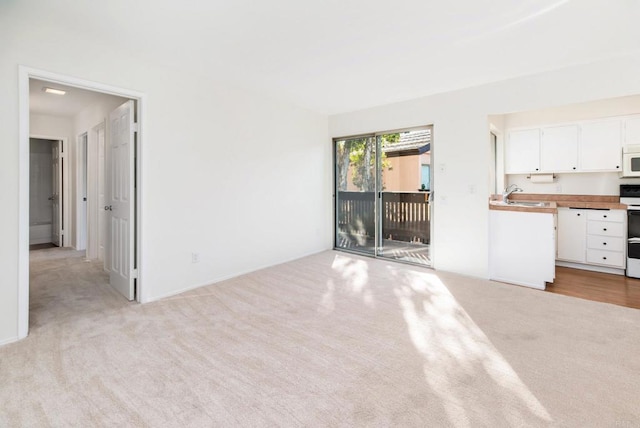 unfurnished living room with sink and light carpet