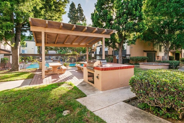 view of community featuring a pergola, a pool, exterior kitchen, and a patio