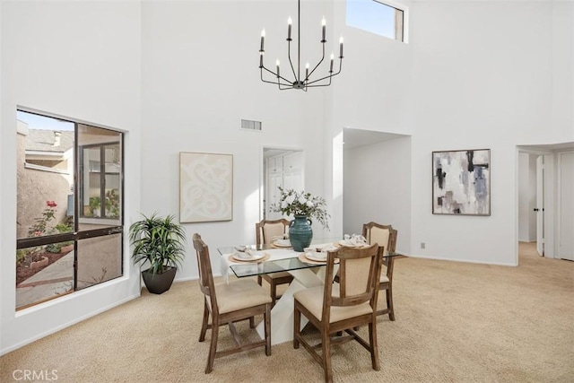 carpeted dining room with a high ceiling and an inviting chandelier