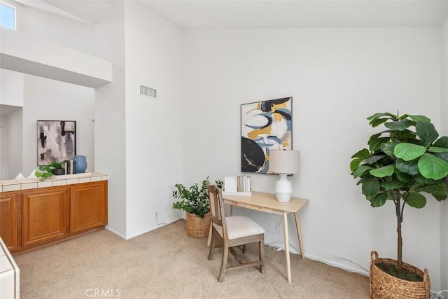 office featuring light colored carpet and a towering ceiling