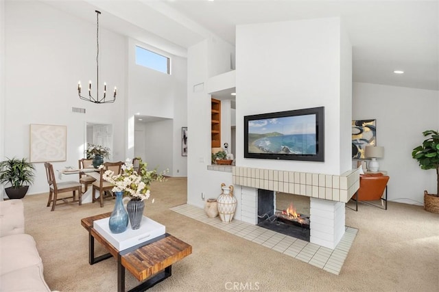 carpeted living room with a notable chandelier, a towering ceiling, and a fireplace