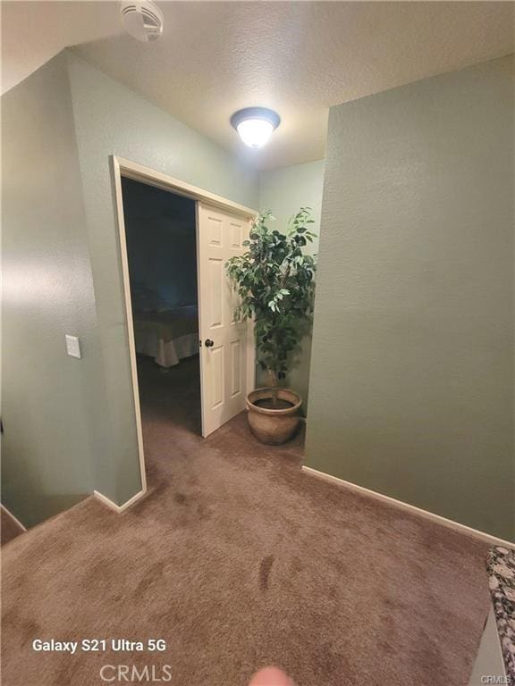 hallway with a textured ceiling and carpet