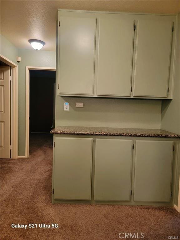 kitchen with light colored carpet and a textured ceiling