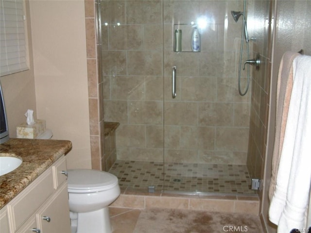 bathroom with a shower with door, vanity, and toilet