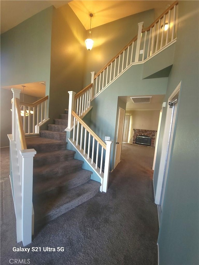 stairway with a fireplace, carpet, and a high ceiling