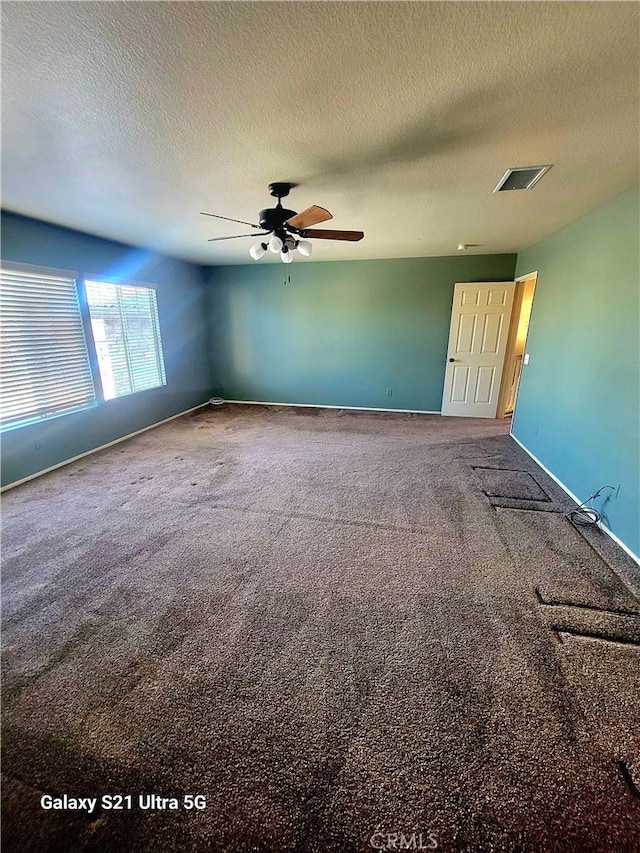 empty room with ceiling fan, carpet, and a textured ceiling