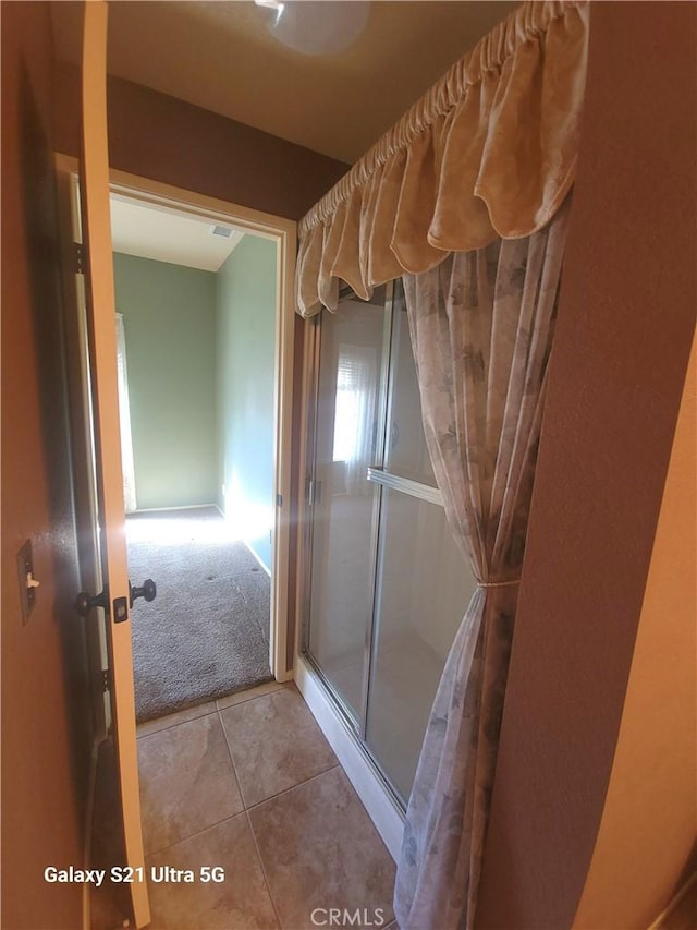 bathroom with tile patterned flooring and a shower with shower door