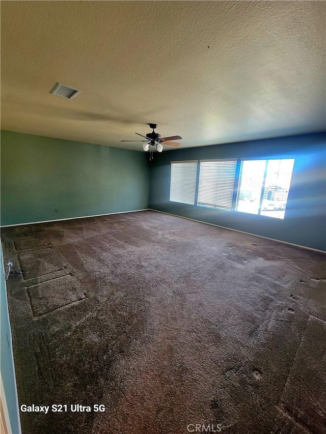 empty room featuring ceiling fan, a textured ceiling, and carpet