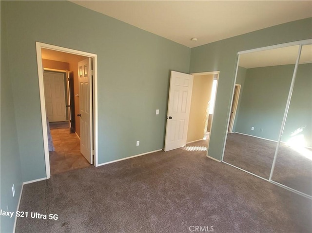 unfurnished bedroom featuring dark carpet and a closet