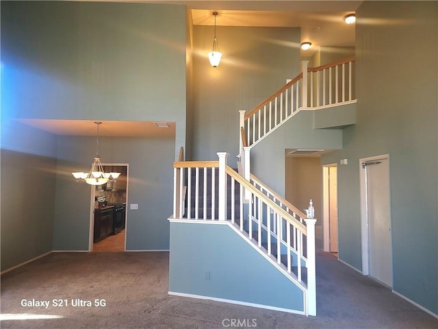 staircase featuring a high ceiling, carpet floors, and a notable chandelier