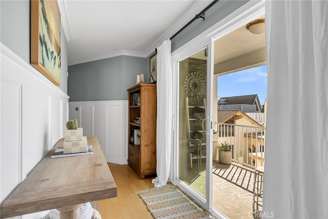 doorway with crown molding and light hardwood / wood-style floors