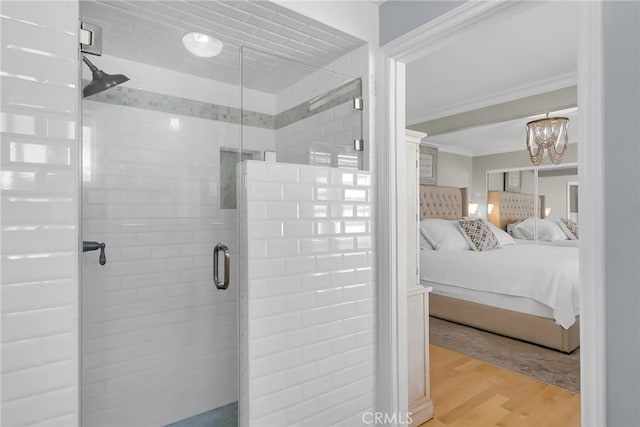 bathroom featuring hardwood / wood-style flooring, crown molding, an enclosed shower, and an inviting chandelier