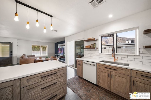 kitchen featuring white dishwasher, sink, decorative light fixtures, and decorative backsplash