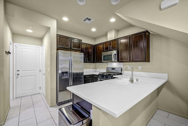 kitchen featuring dark brown cabinetry, stainless steel appliances, sink, kitchen peninsula, and a breakfast bar