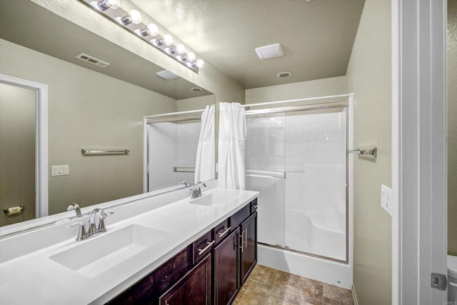 bathroom with vanity, a textured ceiling, and walk in shower