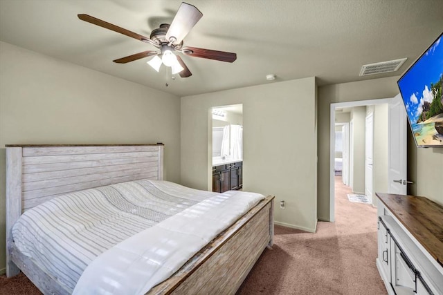 bedroom with ceiling fan, light carpet, and ensuite bathroom