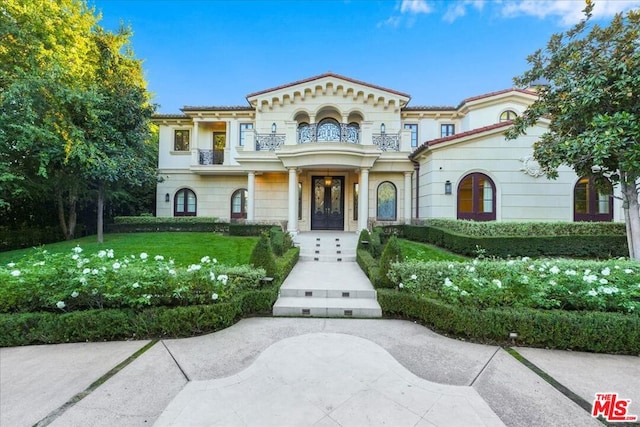 mediterranean / spanish-style house featuring a front yard and a balcony