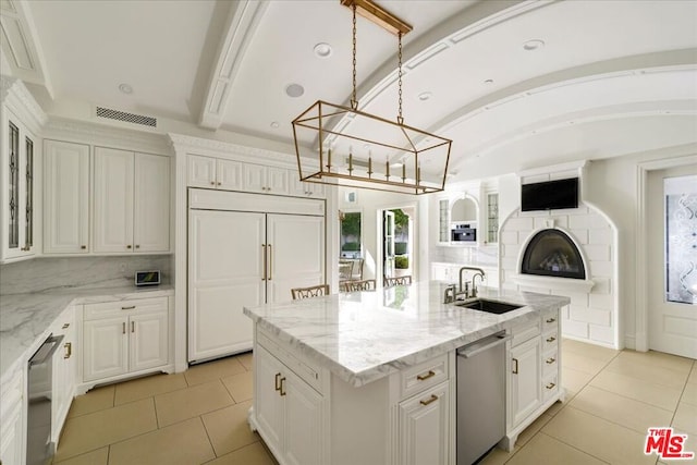 kitchen featuring lofted ceiling, white cabinetry, an island with sink, sink, and paneled fridge