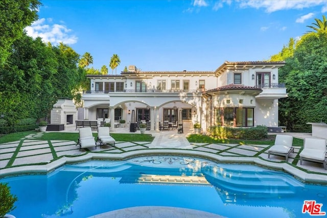 back of house with a balcony, a fireplace, and a patio area