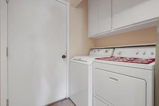 laundry area featuring cabinets, light tile patterned floors, and separate washer and dryer