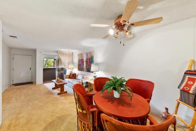 carpeted dining room with ceiling fan and a textured ceiling