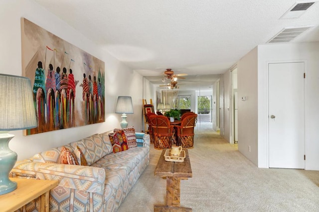 living room featuring ceiling fan, light colored carpet, and a textured ceiling