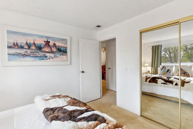 bedroom with light colored carpet, a textured ceiling, and a closet