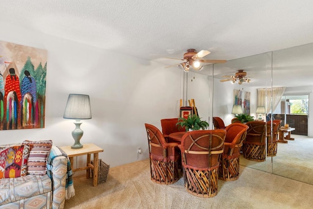 carpeted dining area featuring ceiling fan and a textured ceiling