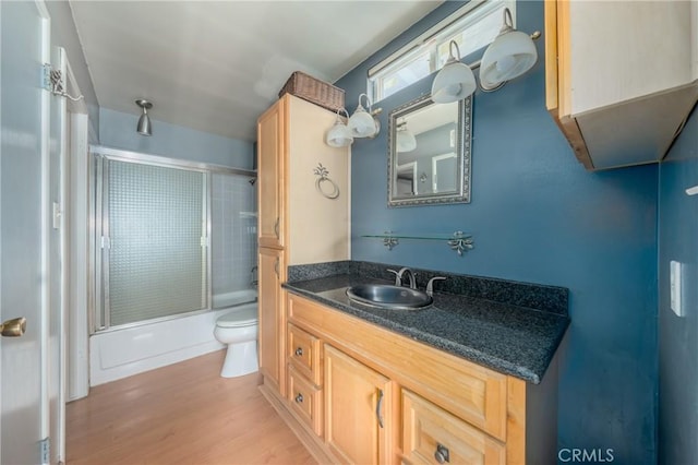 full bathroom featuring toilet, enclosed tub / shower combo, wood-type flooring, and vanity