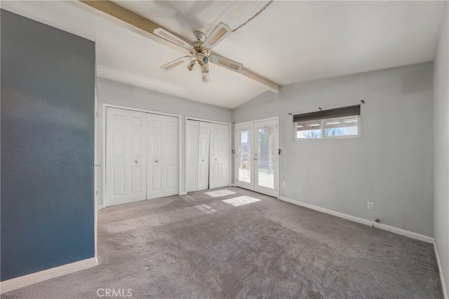 unfurnished bedroom featuring carpet floors, two closets, french doors, lofted ceiling with beams, and ceiling fan