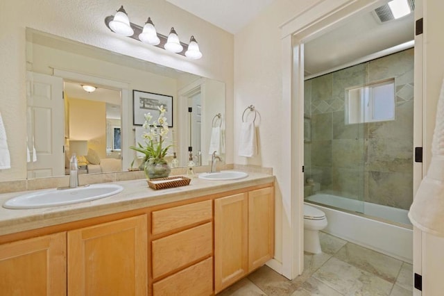 full bathroom featuring shower / bath combination with glass door, vanity, and toilet