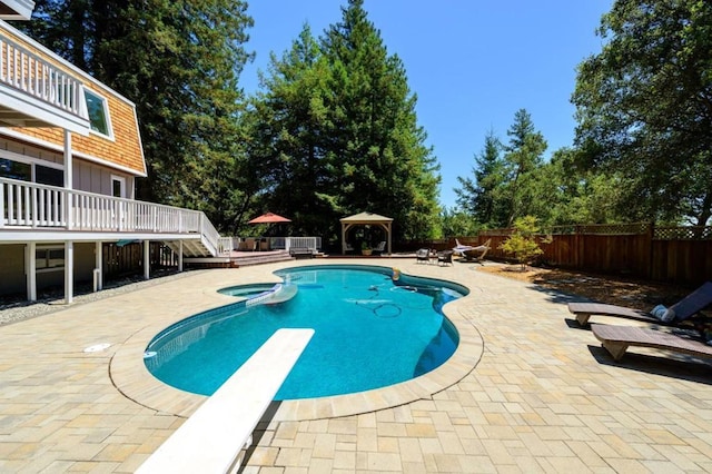 view of pool featuring an in ground hot tub, a gazebo, a wooden deck, a diving board, and a patio