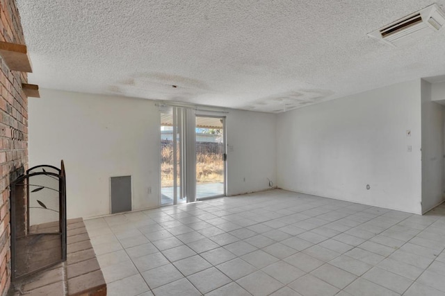 spare room with light tile patterned floors, a fireplace, and a textured ceiling