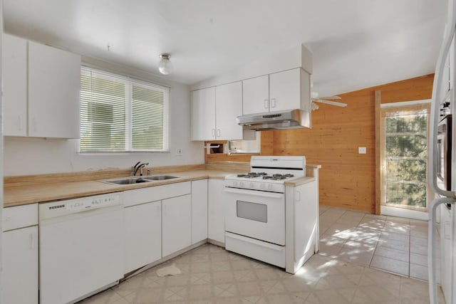 kitchen with white cabinetry, sink, white appliances, and wood walls