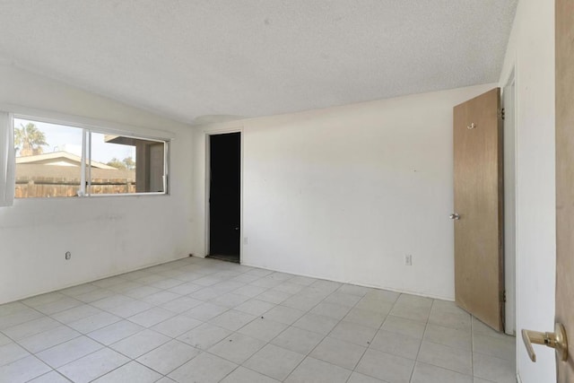 unfurnished room with vaulted ceiling and a textured ceiling