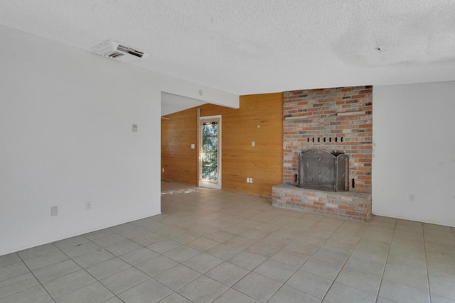 unfurnished living room featuring vaulted ceiling, a textured ceiling, a fireplace, and wood walls