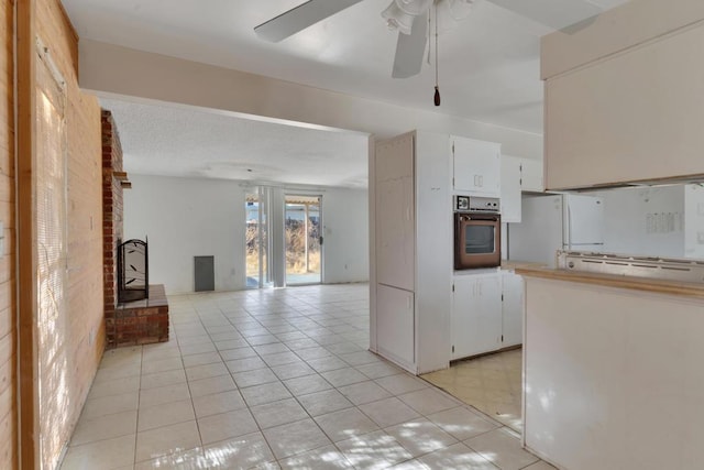 kitchen with brick wall, white cabinets, white fridge, wall oven, and ceiling fan