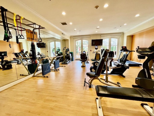 workout area featuring light wood-type flooring and ornamental molding