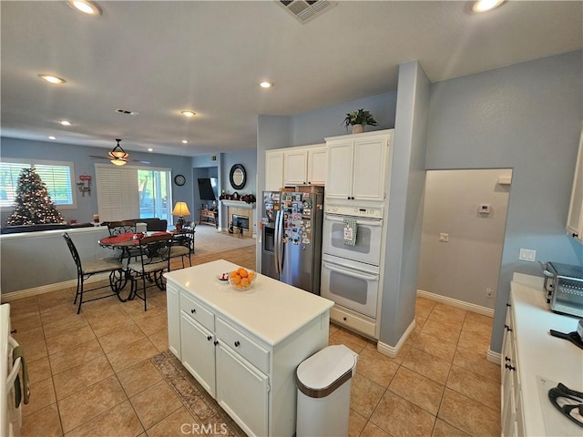 kitchen with ceiling fan, a center island, light tile patterned flooring, white cabinetry, and stainless steel fridge