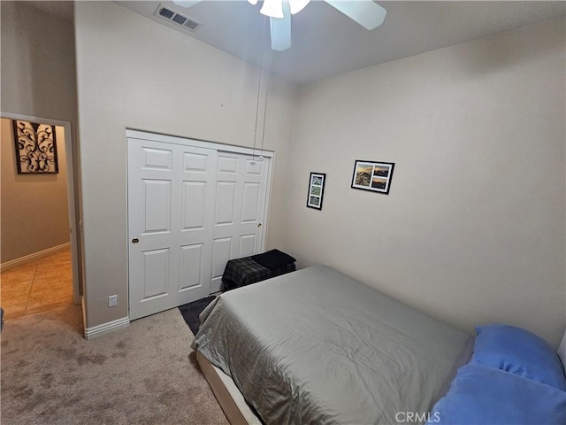 bedroom with light carpet, ceiling fan, and a closet