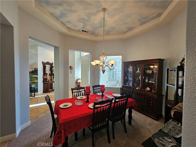 carpeted dining space with a tray ceiling and a notable chandelier