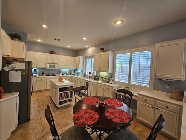 kitchen featuring light tile patterned floors, fridge, gas stovetop, and a center island