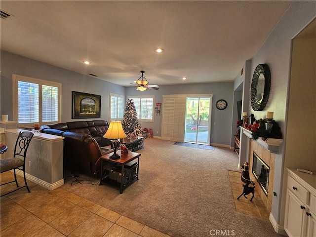 living room featuring ceiling fan, light colored carpet, and a tiled fireplace