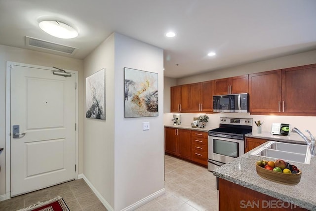 kitchen featuring light stone counters, sink, and stainless steel appliances