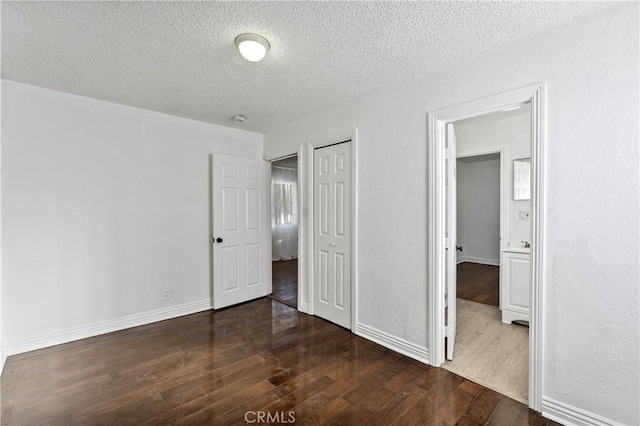 unfurnished bedroom with a closet, dark hardwood / wood-style flooring, and a textured ceiling