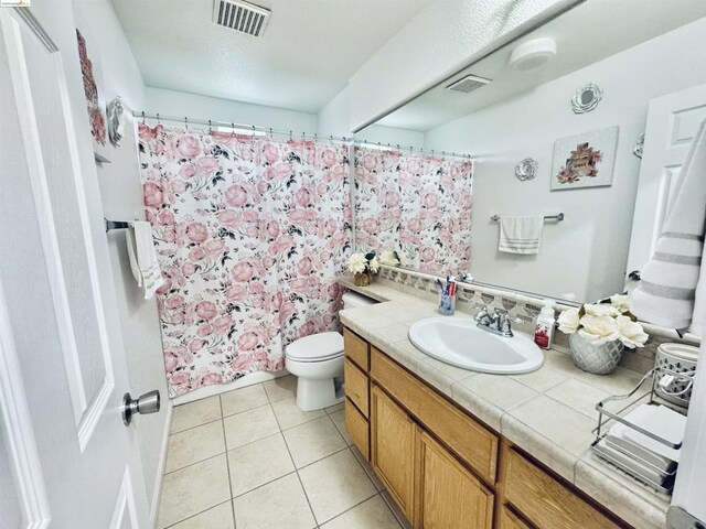 bathroom featuring toilet, tile patterned flooring, tasteful backsplash, and vanity