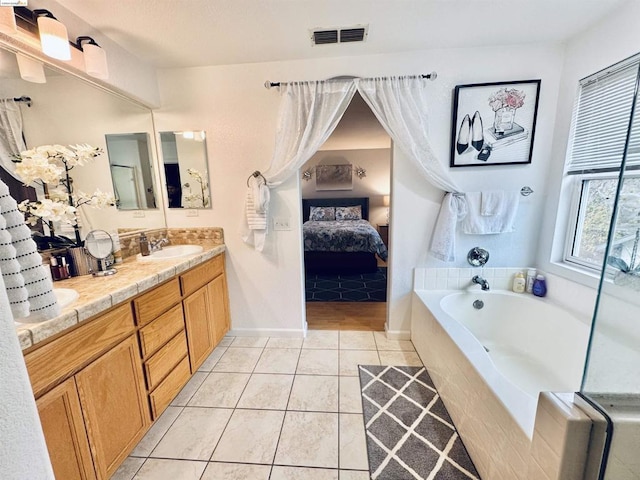 bathroom featuring tiled tub, tile patterned floors, and vanity