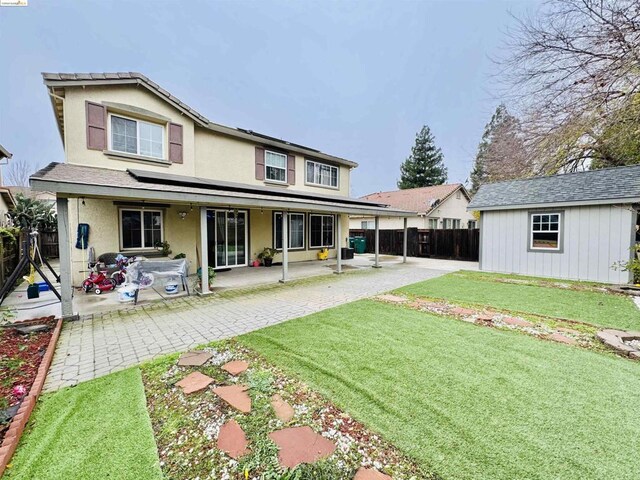 back of property featuring a patio area, a shed, and a lawn